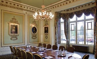 a conference room with a large table and multiple chairs , surrounded by paintings and a chandelier at Mercure Blackburn Dunkenhalgh Hotel & Spa