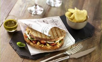 a sandwich is served on a plate with a side of fries and a knife at Ibis Sydney Airport