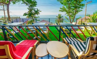 a balcony overlooking the ocean , with a variety of colorful lounge chairs and tables placed on the balcony at Play Phala Beach Rayong