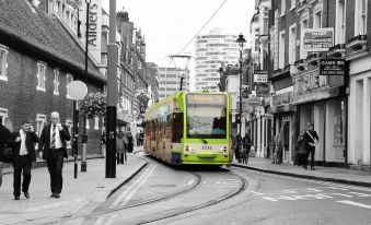 a green and yellow tram is traveling down a street in an urban setting , surrounded by buildings and people at Lansdowne Hotel