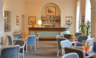 a dining room with a table and chairs , along with a bar area with chairs and a sink at Grand Hotel Menaggio