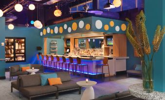 a modern lounge area with a bar and couches , featuring colorful lights and spherical decorations at The Moonrise Hotel