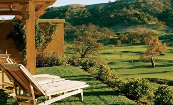 a wooden deck chair is placed on a grassy hillside with a beautiful view of the surrounding landscape at CordeValle