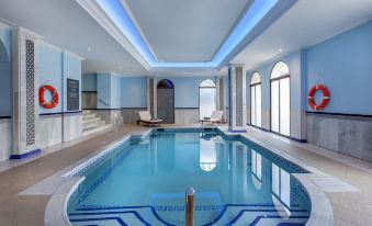 an indoor swimming pool surrounded by a spa area , with several people enjoying their time in the water at Barcelo Isla Canela Hotel