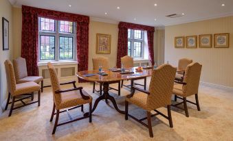 a dining room with a wooden table surrounded by chairs , and a window providing natural light at Lucknam Park Hotel