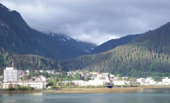 a view of a mountainous landscape with a river and buildings in the foreground , under a cloudy sky at The Driftwood Lodge