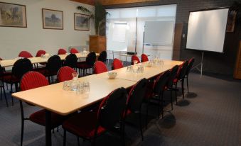 a conference room with a long table , chairs , and a whiteboard , set up for a meeting or presentation at The Wine Vine Hotel