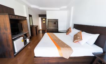 a large bed with a white and orange blanket is in a room with wooden floors at Diamond Park Inn Chiangrai & Resort