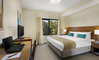 a hotel room with a comfortable bed , a desk , and a tv . also a chair in the room at Quest Bendigo Central