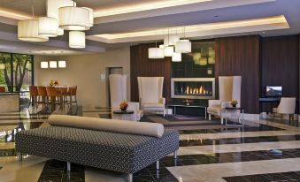 a modern hotel lobby with a large fire place , white chairs , and wooden furniture arranged around the space at Crowne Plaza Suffern-Mahwah, an IHG Hotel