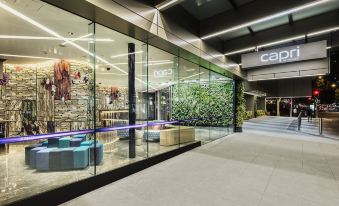 a modern building with a glass facade and a large logo on the side of the building at Capri by Fraser Brisbane