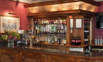 a well - stocked bar with numerous bottles of various liquors and a variety of wine glasses on display at Berjaya Eden Park London Hotel