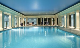 an indoor swimming pool surrounded by windows , with lounge chairs and a dining table nearby at Cbh Hythe Imperial Hotel Golf and Spa