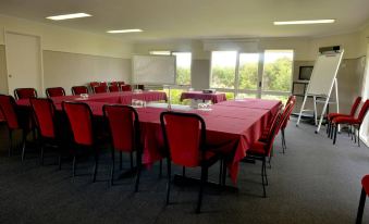 a large conference room with red chairs arranged in rows , a table , and a window at Sanctuary Inn on Westernport