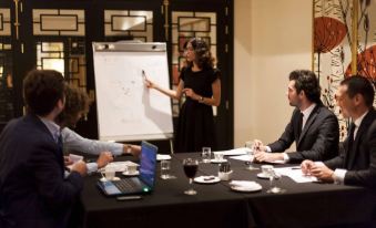 a group of people are gathered around a table , engaged in a meeting with a whiteboard and laptop at Hotel Pulitzer Buenos Aires