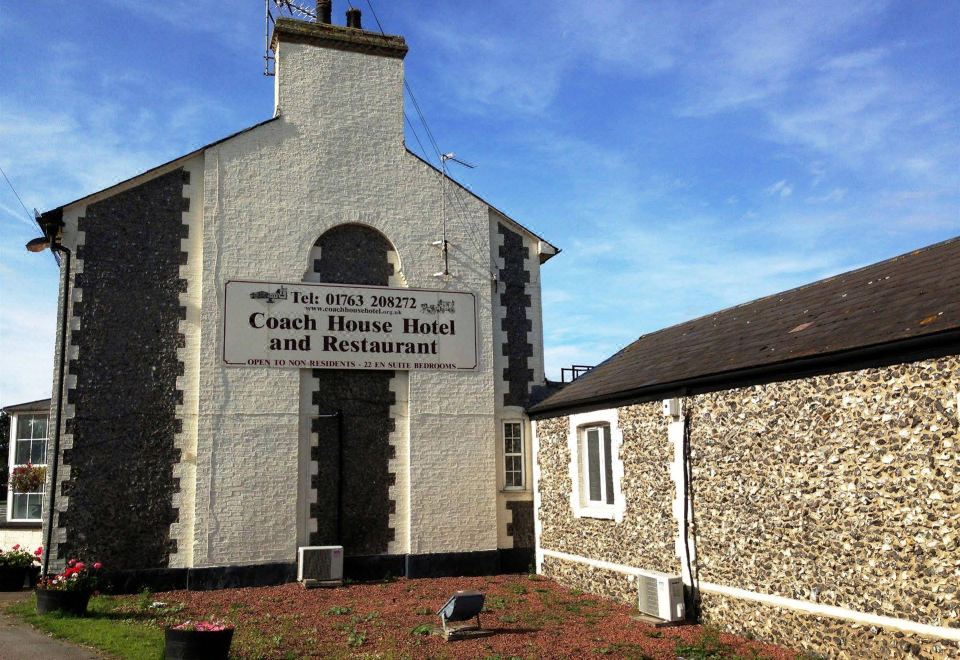 "a brick building with a sign that reads "" coach house hotel "" prominently displayed on the front of the building" at Coach House Hotel