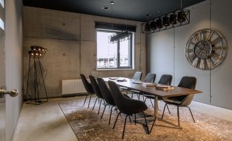 a conference room with a large wooden table surrounded by black chairs and a large window at Moxy Edinburgh Airport