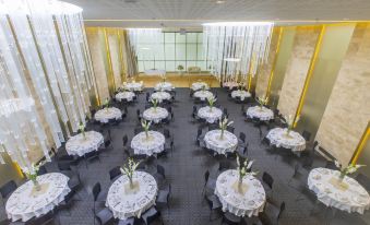 a large room with multiple round tables covered in white tablecloths and chairs arranged in rows at Holiday Inn Algiers - Cheraga Tower