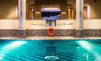 an indoor swimming pool with a red life preserver floating on the water , surrounded by white columns and a high ceiling at Radisson Blu Hotel, Szczecin