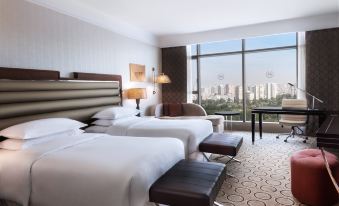 a modern hotel room with two beds , a desk , and a view of the city at Sheraton Grand Adana