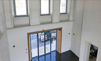 a large open doorway with white walls and wooden floor leads to a white room with two windows , a black floor and gray carpet at Fleur de LIS