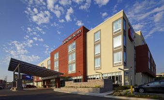 a large hotel building with a red and beige exterior , situated in front of a parking lot at SpringHill Suites Columbus OSU