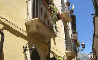 a narrow street in a european city , with yellow buildings on either side and balconies filled with flowers at Legacy