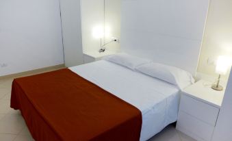 a bed with a white and orange blanket is in a room with a desk and a lamp at Nautilus