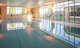 a large indoor swimming pool surrounded by windows , providing a view of the surrounding area at Holiday Inn Ipswich