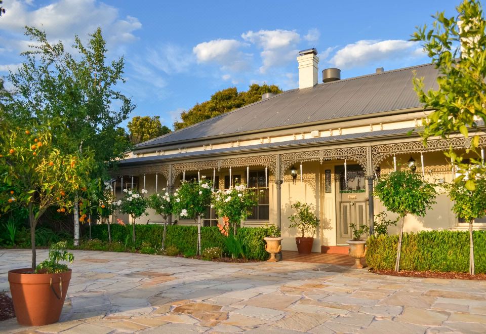 a beautiful white house with a blue roof and tiled roof , surrounded by lush greenery at Brooklands of Mornington