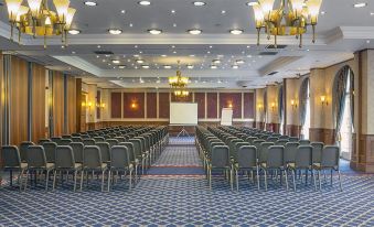a large conference room with rows of chairs arranged in a semicircle , and a projector screen at the front of the room at Quorn Country Hotel