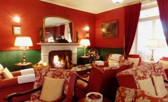 a cozy living room with red and green walls , a fireplace , and a fireplace in the background at Atholl Arms