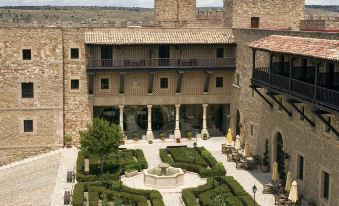 a large , old building with a courtyard in front of it , surrounded by a brick wall at Parador de Siguenza