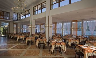 a large , well - lit dining room with numerous tables and chairs arranged for a group of people at Hotel Bazzoni