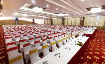 a large conference room filled with rows of white chairs and red and yellow tablecloths at Muong Thanh Grand Quang Nam