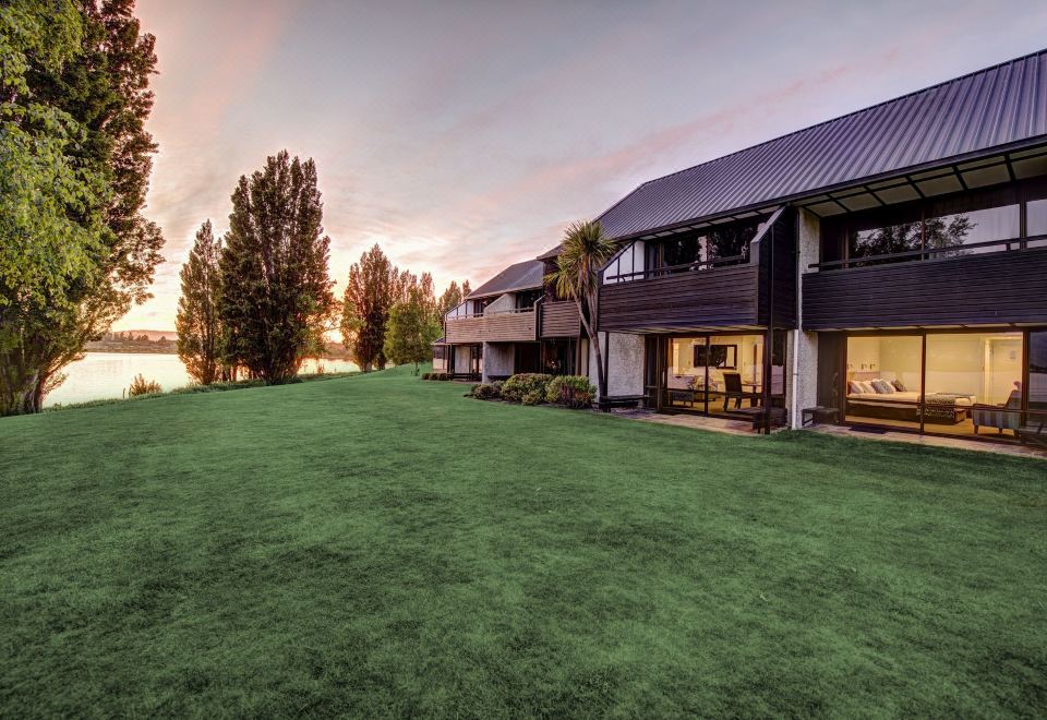 a large , modern house with a grassy yard and a lake in the background , as well as a sunset view from above at Edgewater Hotel