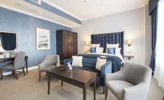 a spacious bedroom with a blue bed , a chair , and a rug on the floor at Cbh Hythe Imperial Hotel Golf and Spa