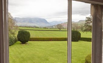 a large window overlooking a lush green field and a grassy field , with mountains in the background at Hundith Hill Hotel