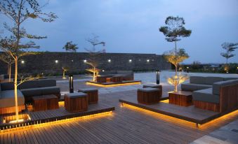 a serene outdoor setting with wooden benches , chairs , and trees illuminated by lights at night at Alila Solo