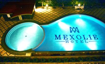 "a large swimming pool with a white building in the background and a sign reading "" mexola hotel "" on it" at Mexolie Hotel