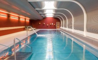 an indoor swimming pool with a red and white color scheme , surrounded by a white ceiling at Hotel Ambassador Zermatt