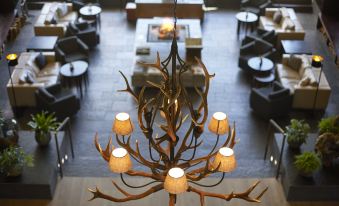 a large chandelier with antlers hanging from the ceiling in a room filled with tables and chairs at Kempinski Hotel Berchtesgaden