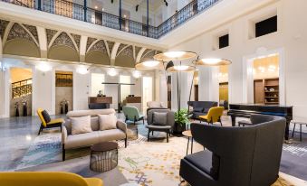 a spacious , modern living room with multiple couches and chairs arranged in various positions , creating a comfortable and inviting atmosphere at Hotel Moments Budapest