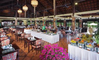 a large dining room filled with tables and chairs , where people are enjoying a buffet - style meal at Pandanus Resort