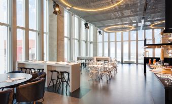a modern office space with large windows , modern furniture , and a bar area under the sun at Nhow Rotterdam