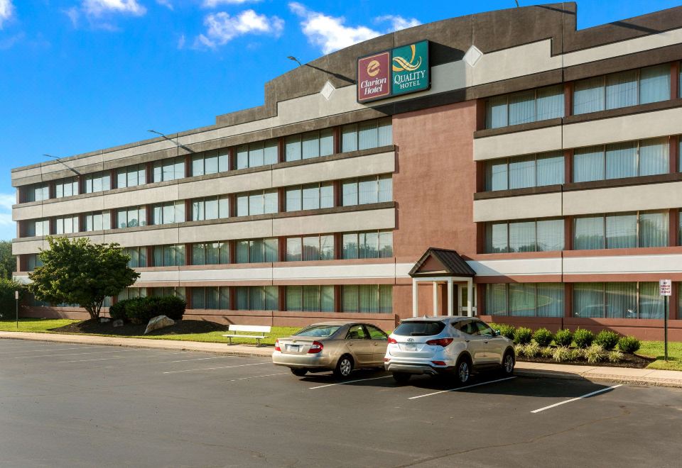 a hotel building with a large parking lot in front , where two cars are parked at Chester Hotel and Conference Center