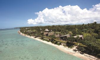 aerial view of a tropical island with a sandy beach , lush greenery , and a small village at Shangri-La Yanuca Island, Fiji