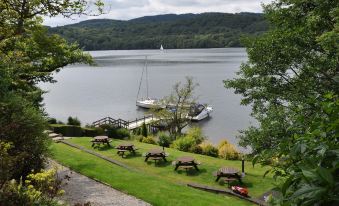 a serene lake with boats docked , surrounded by lush green trees and picnic tables on the shore at Beech Hill Hotel & Spa