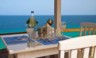 a dining table set up for a meal , with a view of the ocean in the background at Blue Bay Halkidiki