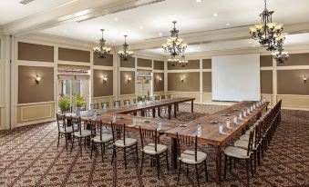 a large conference room with a long table , chairs , and chandeliers , set up for a meeting at The Inn at Rancho Santa Fe